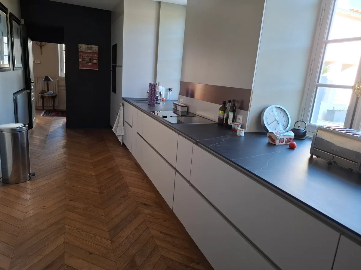 Cuisine équipée avec plan de travail, rangements et parquet