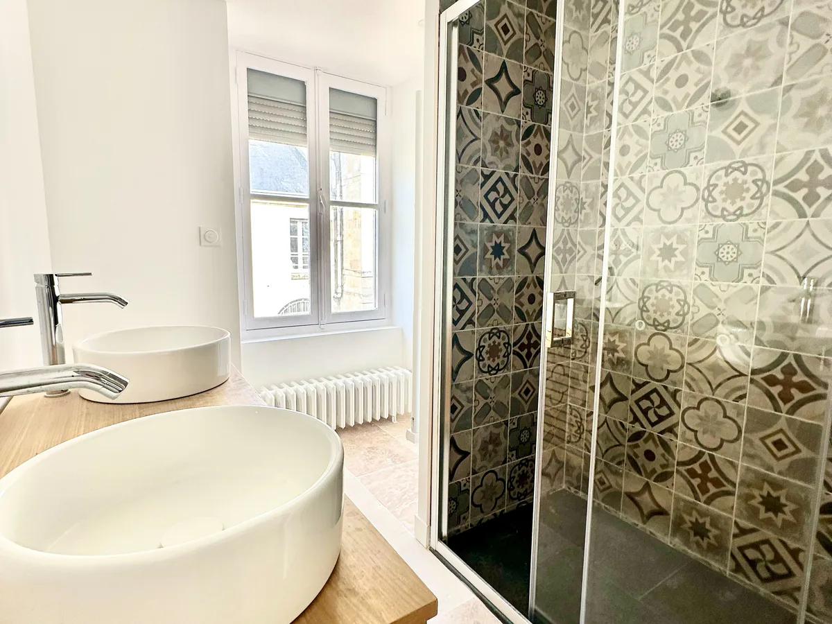 Salle de bain avec vasques, douche et faïence décorative